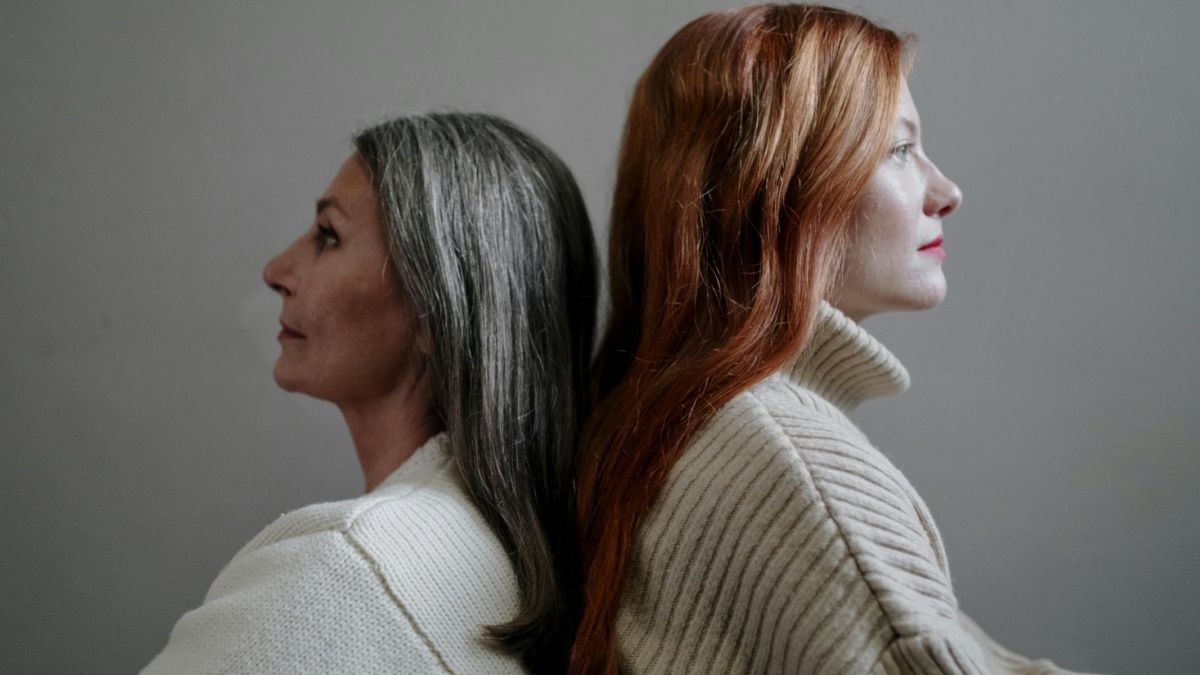 foto di due donne con divere età con sfondo grigio che si tramandando la gestualità della skincare