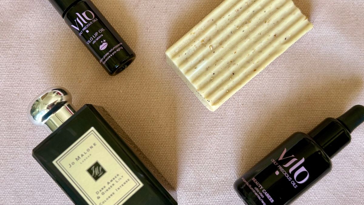 in questa foto si vede il prodotto di vilo cosmetics. l'olio viso illuminate,levigante Beauty Caress e il vilo lip oil su uno sofndo neutro, inseme a un sapone viso e al profumo ginger lilly di jo malone