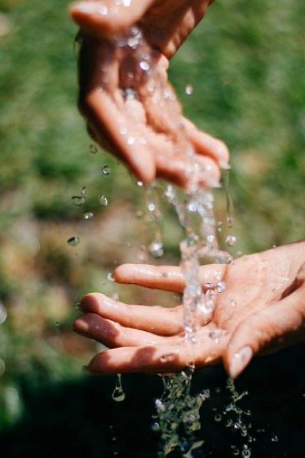 Mani di giovane donna attraversate da una cascata di acqua