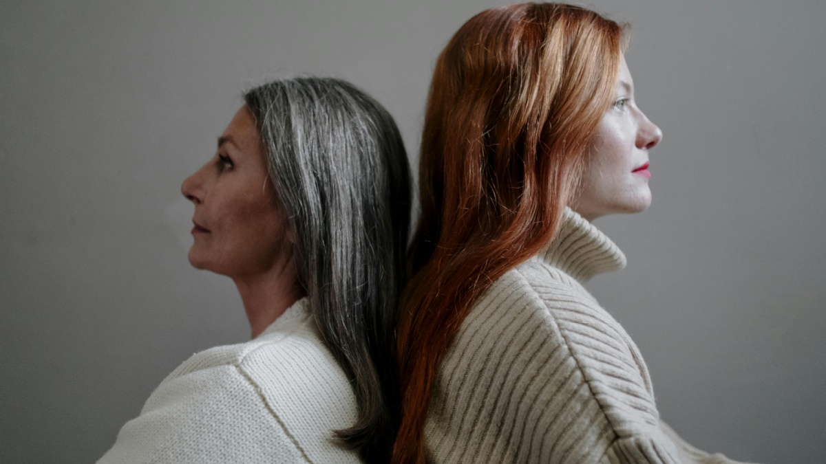 foto di due donne con divere età con sfondo grigio che si tramandando la gestualità della skincare