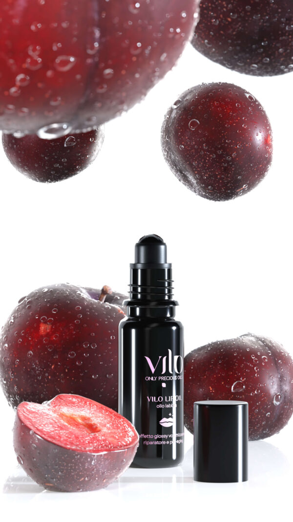 Foto di prodotto del balsamo per labbra olio labbra vilo lip oil con a fianco delle prugne