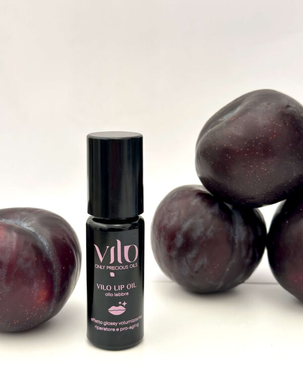 Foto di prodotto del balsamo per labbra olio labbra vilo lip oil con a fianco delle prugne